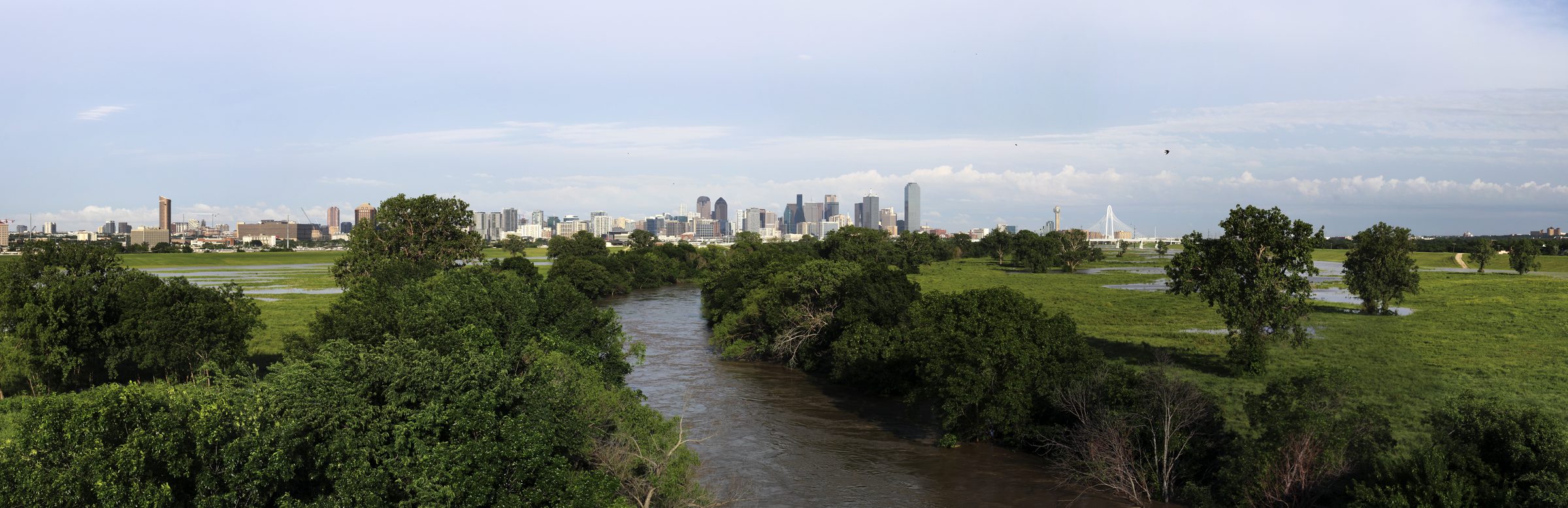 The Dallas skyline seen across the Trinity River and its green banks on a bright spring day